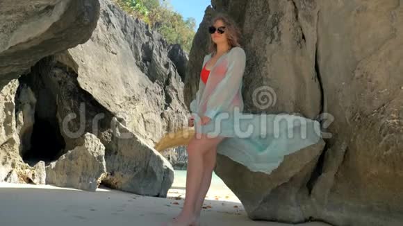 站在岩石中间的年轻漂亮女孩在岩石间摆姿势的漂亮模特视频的预览图