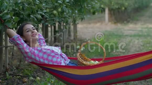收获季节带着水果篮的微笑女性躺在吊床上享受放松视频的预览图