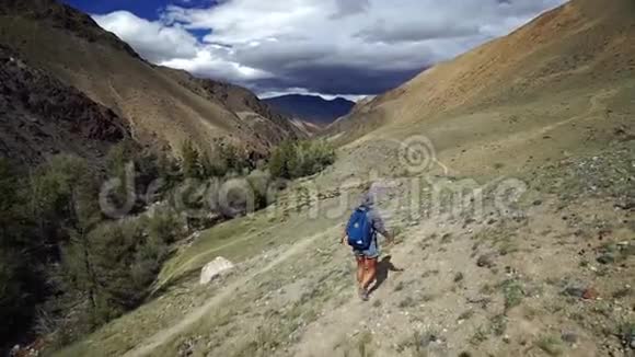 勇女背着背包爬上石山天空和山的背景都是云视频的预览图