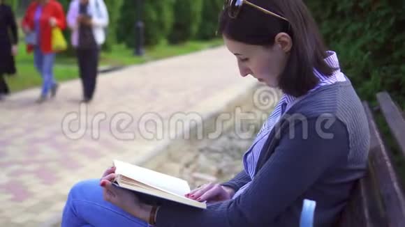 坐在长凳上拿书的可爱女孩视频的预览图