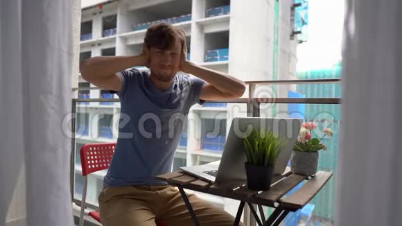 一个年轻人拿着笔记本坐在阳台上被一个人发出的一声巨响所伤视频的预览图
