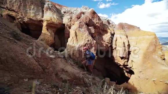 年轻的旅游妇女在阳光明媚的日子里爬上一座红石山有风景优美的岩石背景有洞穴视频的预览图