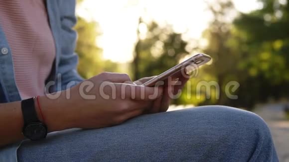 在一个绿色背景的公园里一个漂亮的女人在智能手机上打字瞄准射击视频的预览图