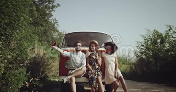 三个朋友一起玩得很开心穿着复古时尚的衣服在路边的橙色老式公共汽车旁边视频的预览图