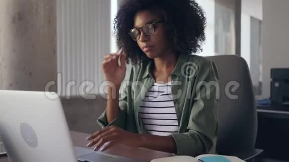 在办公室里用笔记本电脑的年轻女商人精疲力竭视频的预览图