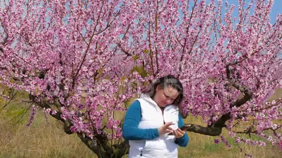 女孩是在一棵开花的树的背景下拍摄的视频的预览图