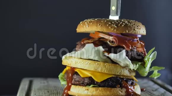 一个大汉堡里面有双切蔬菜和芝麻包上面插着一把刀视频的预览图
