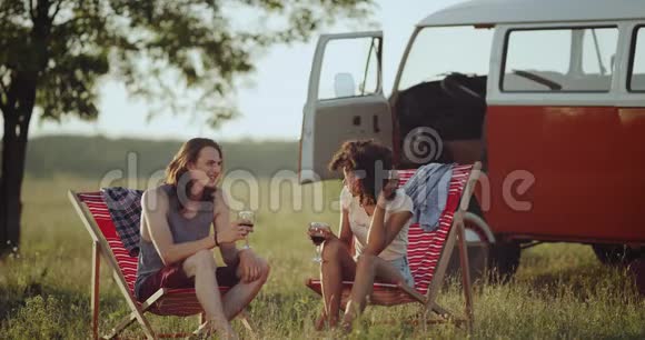 与大自然中的一杯葡萄酒进行了愉快的交谈两个朋友非洲女人和年轻人坐在上面视频的预览图
