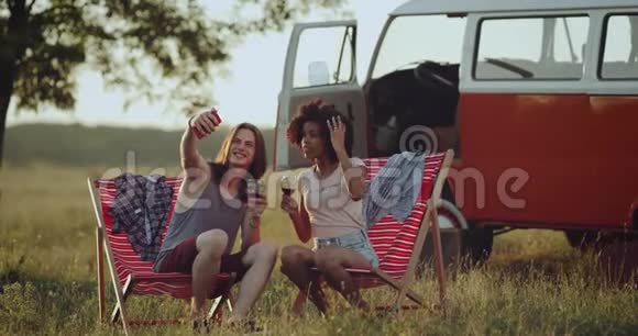 在野餐时一对多文化的好夫妇的自拍时间在自然的景色中带着日落喝着玻璃视频的预览图