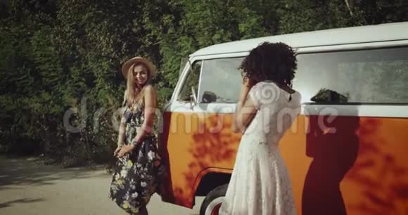 在她的非洲朋友女朋友的面前在复古的公共汽车后面微笑着跳舞视频的预览图
