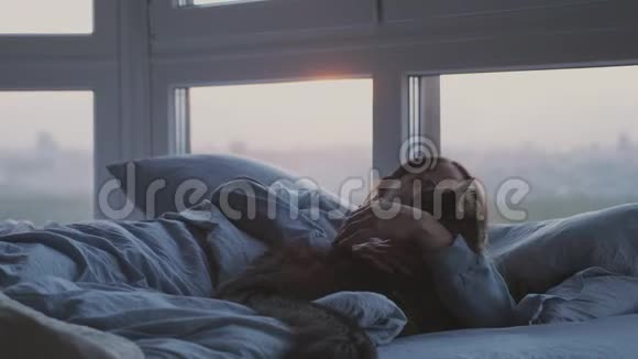 早上美丽的黑发女人醒来躺在床上打哈欠她的缅因州猫在她的房间旁边视频的预览图