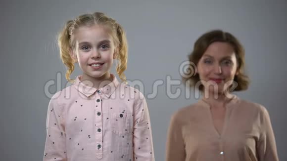 小女孩对着镜头微笑成年女士站在后面孩子们的美好回忆视频的预览图