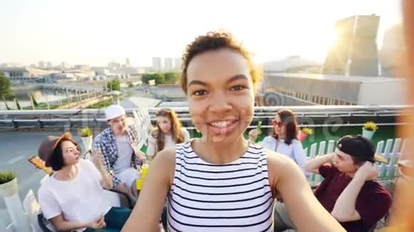 性格开朗的非裔美国女孩正在自拍调整相机然后打电话给她的朋友摆姿势笑着视频的预览图