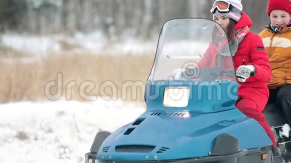 冬天一个年轻的女人和小男孩骑着雪车视频的预览图