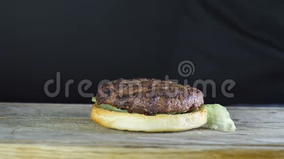 为一个汉堡做一个半个面包上面有一片生菜和一个切块厨师在上面放了两片视频的预览图
