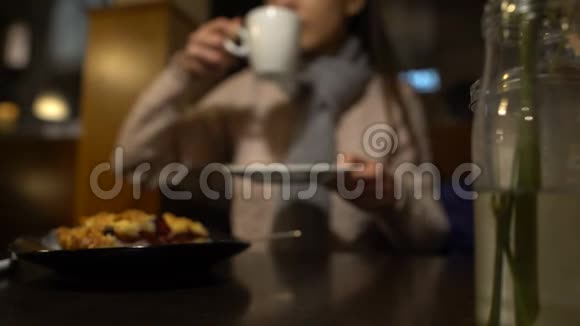 女孩坐在咖啡馆里享受美味的咖啡和甜点等待朋友视频的预览图