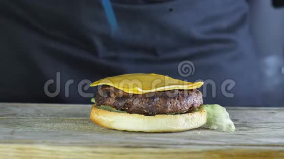 一个汉堡的半个面包上面有一个生菜切片和两片奶酪厨师用煤气火炬视频的预览图