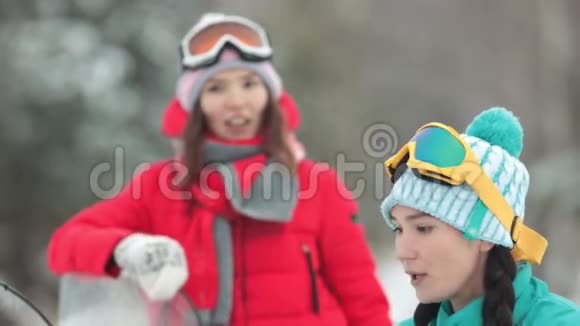 冬天两个穿着五颜六色衣服的年轻女子准备骑雪地摩托视频的预览图