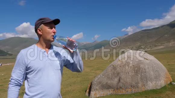 山上阳光明媚的一天戴着瓶盖喝水的旅行者画像视频的预览图
