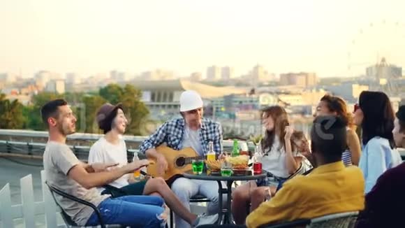 学生们在屋顶上玩得很开心弹吉他唱歌跳舞坐在屋顶上的桌子上享受免费的时光视频的预览图