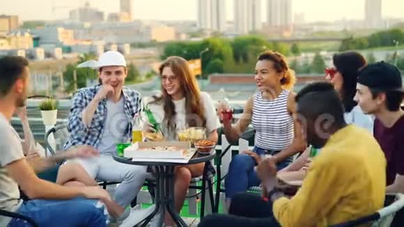 年轻人在喝酒碰瓶子喝啤酒和汽水吃零食聊天笑视频的预览图