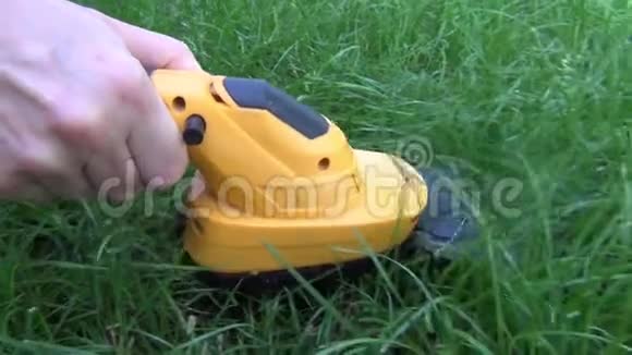 女人在空地上处理一块绿色的草坪上面有一个带有黄色身体的电动修剪器有一个长牙嘴视频的预览图