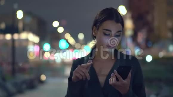 年轻女子在夜城散步和朋友交谈视频的预览图