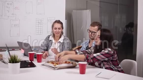 一群男同事和女同事一起在办公室吃披萨年轻的随便穿衣服的员工视频的预览图