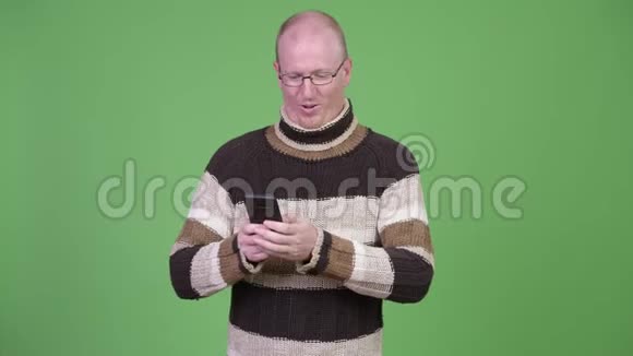 戴着高领毛衣的成熟秃顶男人用电话视频的预览图