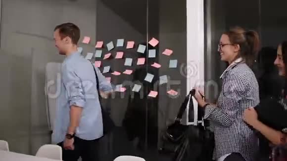 一群积极向上的年轻人带着书包笔记本电脑和文件来上班时微笑着站立站立视频的预览图