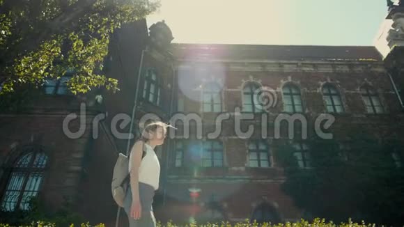 带背包的女孩正与太阳射线和火焰一起沿着历史建筑漫步视频的预览图