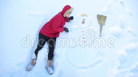 女孩开玩笑躺在雪人高清1080旁边视频的预览图