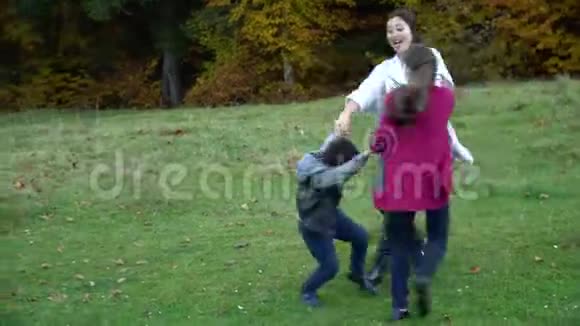 妈妈和她的孩子们正在秋天的森林里玩得很开心他们跳着舞手牵着手他们在笑这就是视频的预览图