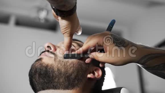 理发师用直剃须刀刮顾客在理发店理发和刮胡子视频的预览图