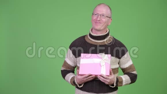 快乐成熟的秃头拿着礼品盒思考视频的预览图