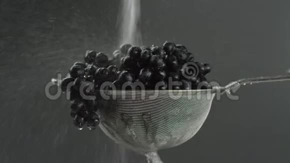 在视频中我们看到葡萄在筛子中水在喷射中从顶部落下然后随着水滴停止灰色的背景视频的预览图