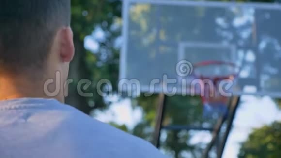 男子背向篮筐向前走击球穿过篮圈在公园玩耍视频的预览图