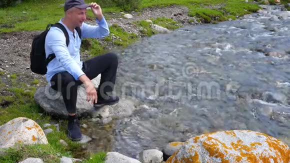 游客坐在石头上的山河和流水的背景视频的预览图