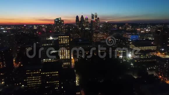 在美丽的4k空中无人机飞行中温暖的橙色傍晚日落天空越过城市明亮的夜光照明城市景观视频的预览图