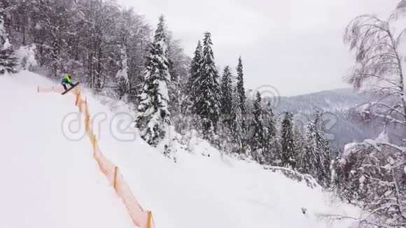 极滑雪者乘坐新鲜粉末雪下陡峭的山坡跳过滑雪道的空中景色视频的预览图