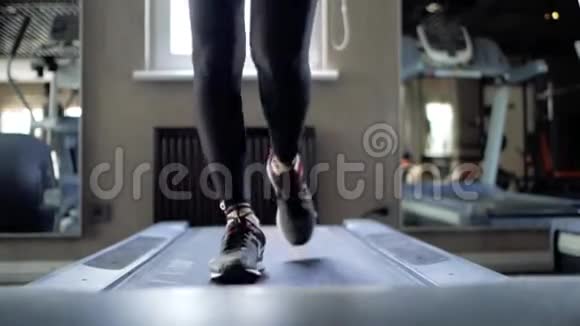 穿着黑色紧身裤和漂亮腿的运动女孩在跑步机上练习视频的预览图