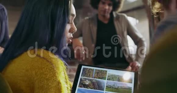 在平板电脑上显示照片和图像的女人多族裔同事和客户群体视频的预览图