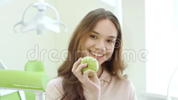 快乐的女人在牙科诊所吃苹果牙科诊所的微笑病人视频的预览图