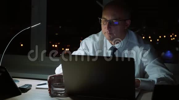 执行职业经理人晚上晚些时候饮用饮用水和笔记本电脑及平板电脑视频的预览图