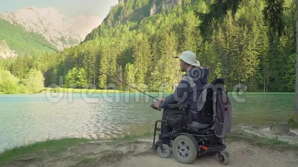 在森林和高山附近美丽的湖泊中残疾渔民在电动轮椅上慢动作捕鱼视频的预览图
