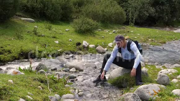 游客在森林中流动的河水中用清水洗手洗脸视频的预览图