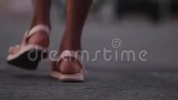 年轻女子穿着凉鞋喝着咖啡散步微笑着坐在城市街道的道路上视频的预览图