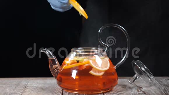 做水果茶酒保把一片橘子放进沸腾的茶壶里里面有不同的水果慢动作视频的预览图