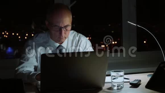 执行职业经理人在深夜微笑着用笔记本电脑工作视频的预览图
