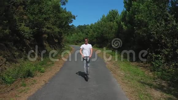 在森林里的路上骑着电动滑板车的年轻人视频的预览图